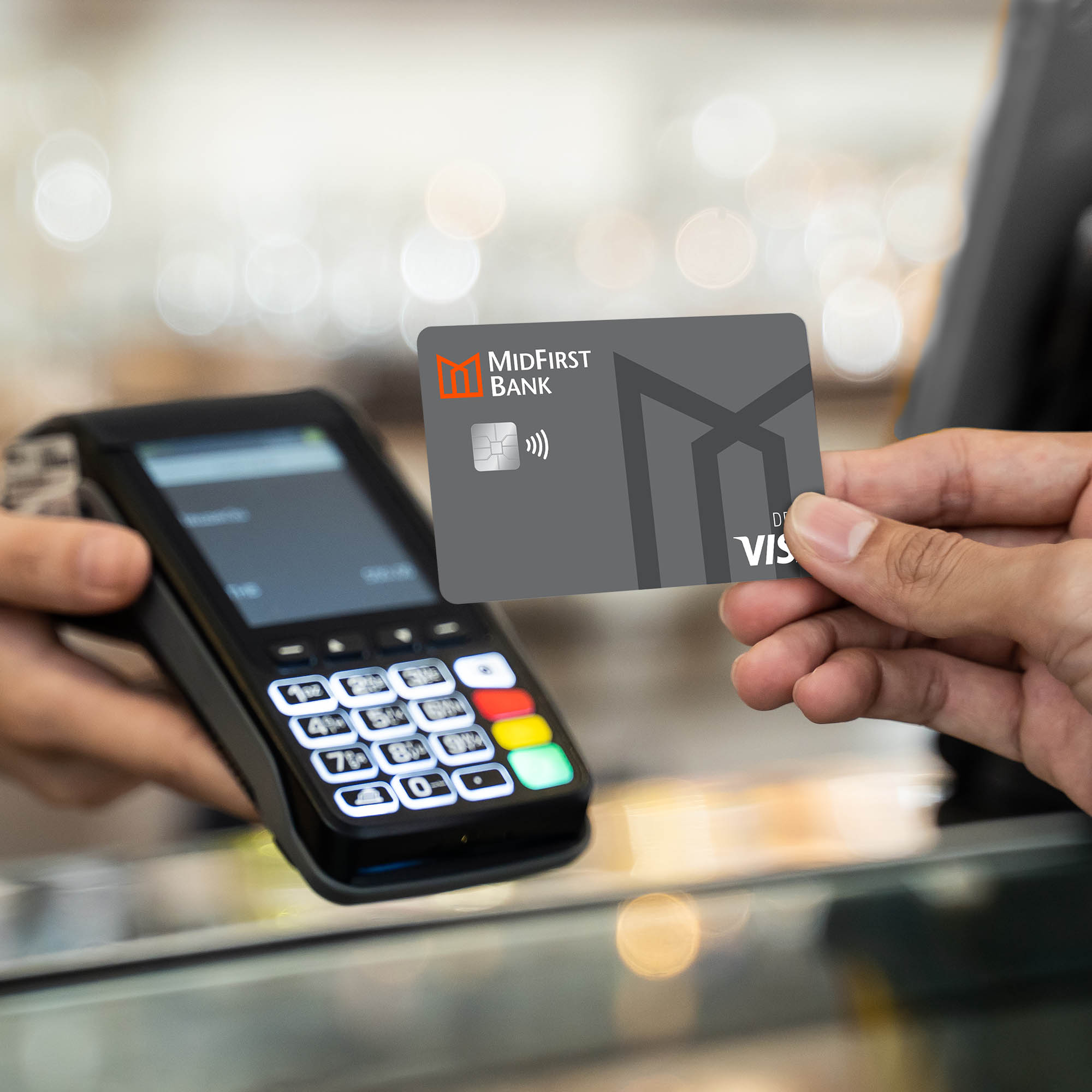 Closeup of a man holding his East First debit card up to a card reader.